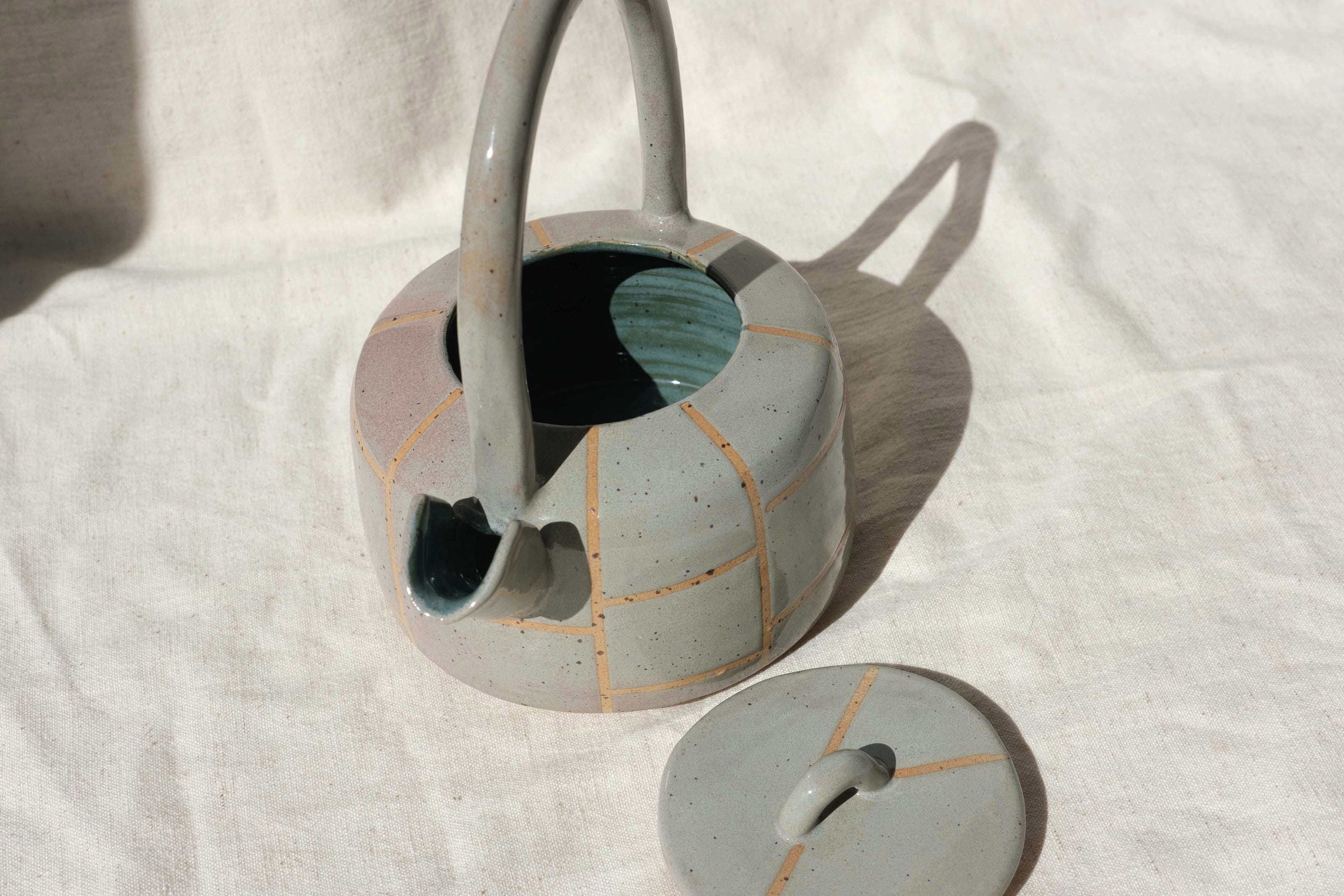 Handmade ceramic teapot creating an intimate and artistic setting. Close-up of the teal green interior with the lid off of the handmade ceramic teapot.