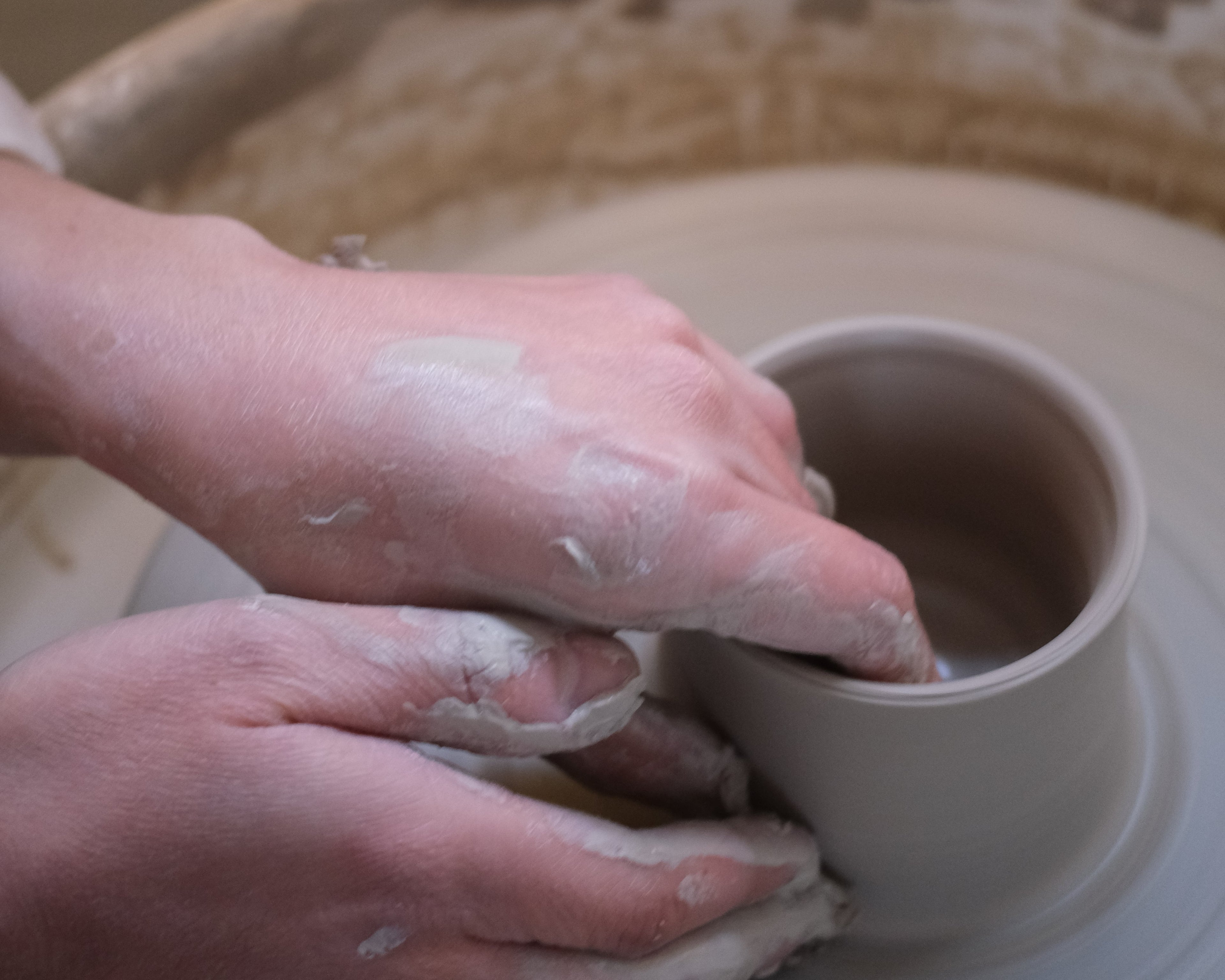 Hands working with clay on a pottery wheel