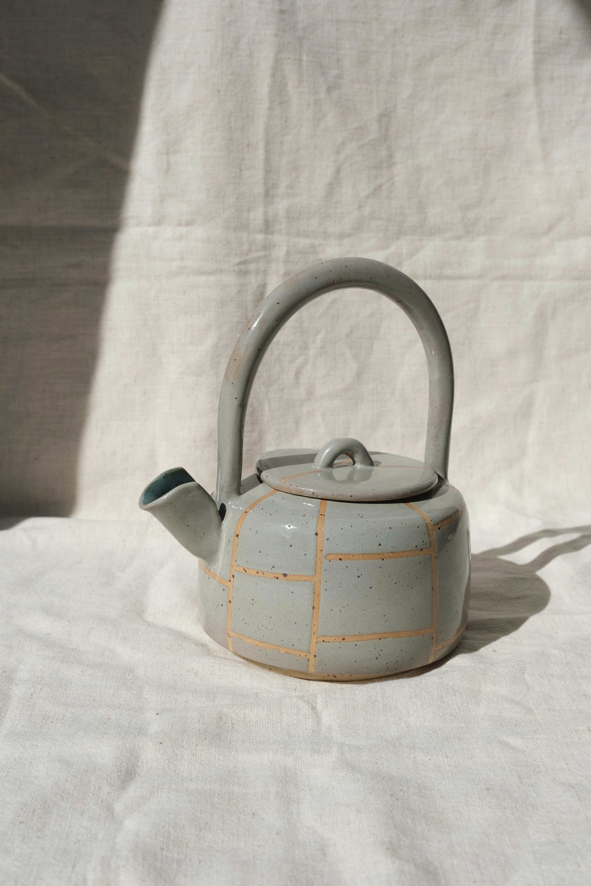 Side view of a handmade ceramic teapot in toasted sage with grid lines